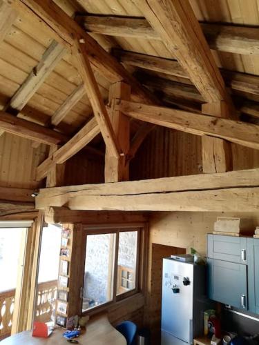 Il comprend une cuisine dotée de plafonds en bois et d'un réfrigérateur. dans l'établissement Joli cocon au pied des montagnes, à La Côte-dʼAime