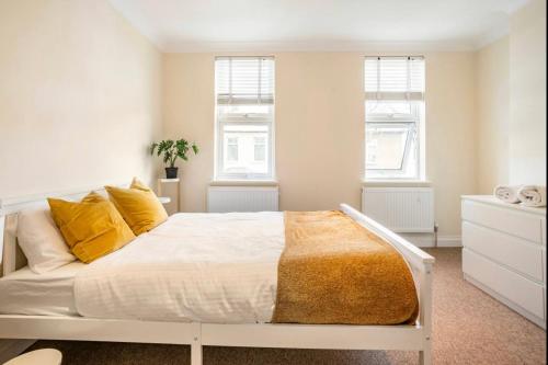 a bedroom with a white bed with yellow pillows at 2 bed terraced house with loft in Stratford London in London