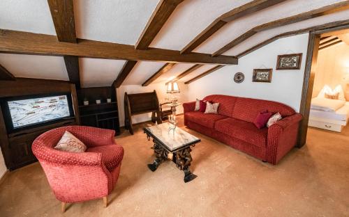 a living room with a red couch and two chairs at Hotel Olympia in Lech am Arlberg