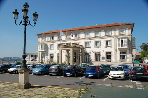 a large building with cars parked in a parking lot at Parador de Ferrol in Ferrol