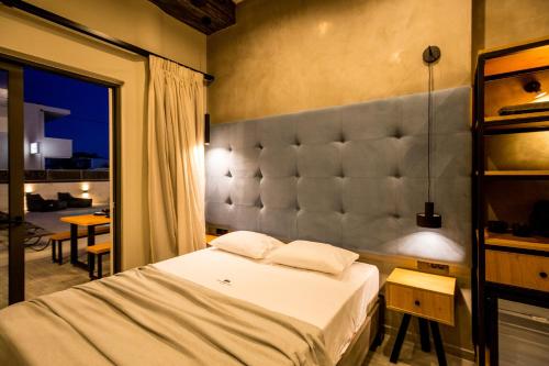 a bedroom with a bed with a large padded headboard at Old Cinema Suites - Stylishly Decorated Retreat with Pool or Jacuzzi by the Sea in the Heart of Laganas Βy Villa Mana Gers in Laganas
