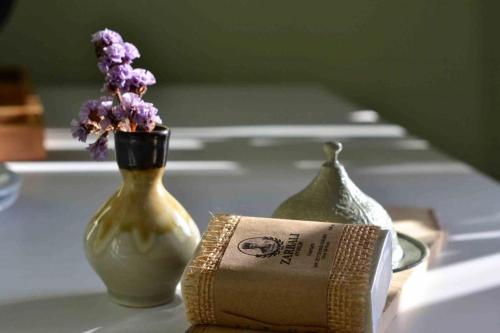a book and a vase with purple flowers on a table at Zarbalı Cunda in Ayvalık