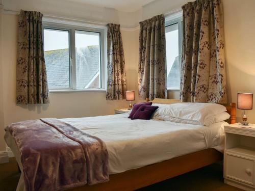 a bedroom with a large bed with two windows at Bayview in Overcombe