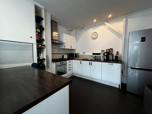 a kitchen with white cabinets and a refrigerator at New 5min TU Delft & city center Garden Room Cleo in Delft