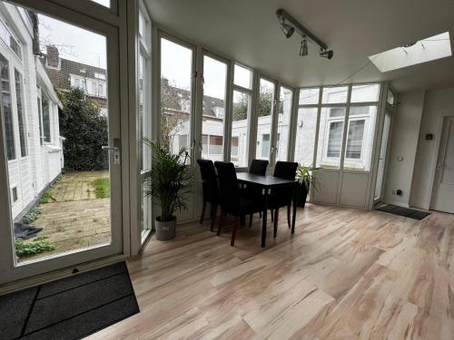 uma sala de jantar com mesa, cadeiras e janelas em New 5min TU Delft & city center Garden Room Cleo em Delft