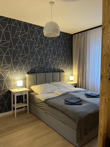 a bedroom with a bed with a black and white wall at Apartament Studio Centrum in Koszalin