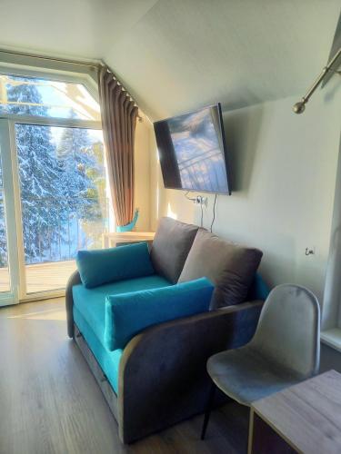 a living room with a blue couch and a window at Отель MONBLAN in Yablunytsya