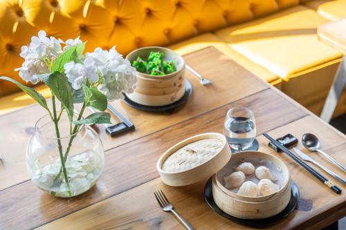 a table with a vase of flowers and a vase of mushrooms at Gaas BaasCo in Kathmandu