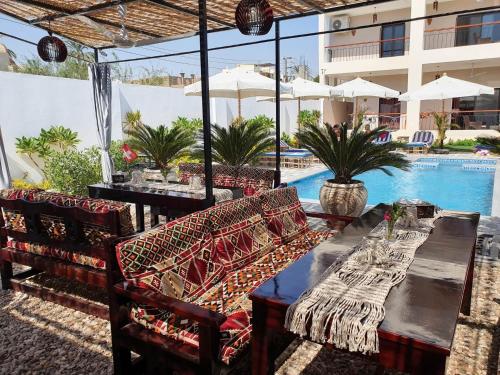 une terrasse avec une table, des chaises et une piscine dans l'établissement CASA LOKO Guest House, à Louxor