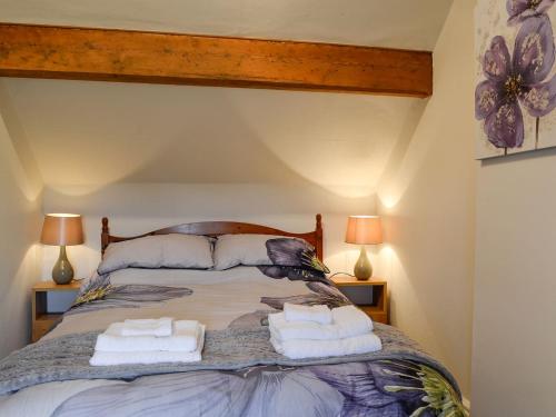 a bedroom with a large bed with two pillows at Rose Cottage in Cleator