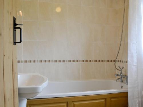 ein Badezimmer mit einer weißen Badewanne und einem Waschbecken in der Unterkunft Rose Cottage in Cleator