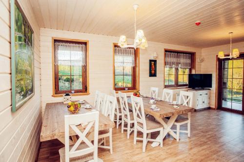a dining room with a wooden table and white chairs at Sielska Chyża in Rzepedż