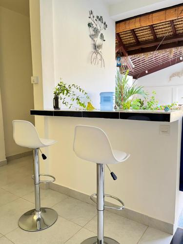 two white bar stools in front of a counter with plants at Villa Cinta Family in Gili Trawangan