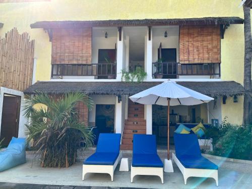 two blue chairs and an umbrella on a patio at Villa Cinta Family in Gili Trawangan