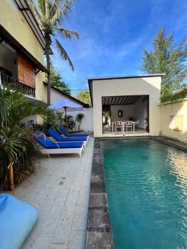 a swimming pool with blue chairs and a house at Villa Cinta Family in Gili Trawangan