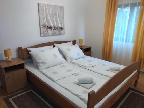 ein Bett mit weißer Bettwäsche und Kissen in einem Schlafzimmer in der Unterkunft Apartments Kesic in Barbat na Rabu
