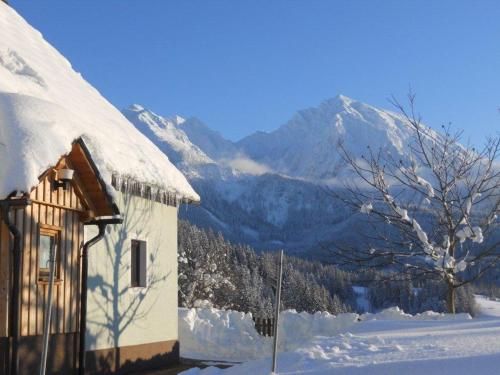 a snow covered house with a mountain in the background at Familienbauernhof Imitz, Ferienwohnung in Spital am Pyhrn