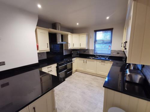 a kitchen with white cabinets and black counter tops at Shared house close to Liverpool city center & LFC/EFC in Liverpool