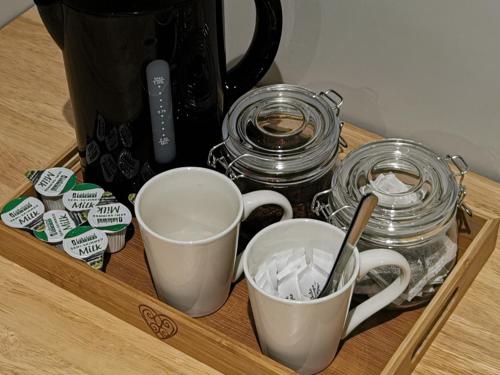 a wooden tray with two cups and jars on a table at Shared house close to Liverpool city center & LFC/EFC in Liverpool