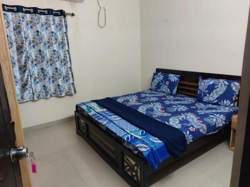 Schlafzimmer mit einem Bett mit blauer Bettwäsche und einem Fenster in der Unterkunft Melody in Hyderabad