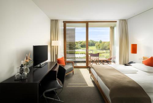 um quarto de hotel com uma cama grande e uma televisão em Angel's - das hotel am golfpark em Sankt Wendel