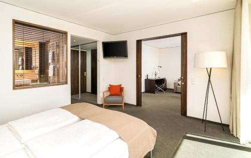 a bedroom with a bed and a chair and a window at Angel's - das hotel am golfpark in Sankt Wendel