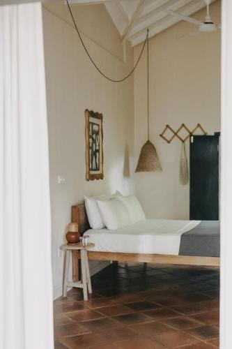 a bedroom with a white bed and a table at The Kip in Ahangama