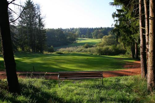 a park bench sitting in the grass near a golf course at Angel's - das hotel am golfpark in Sankt Wendel