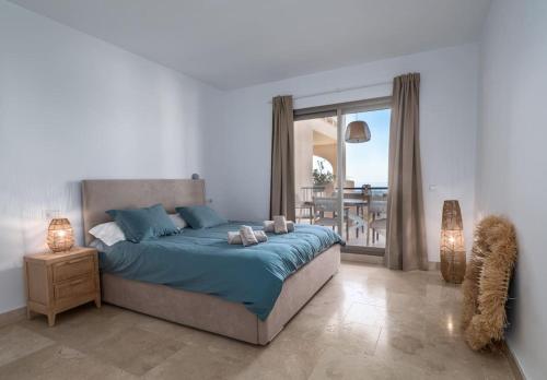 a bedroom with a bed with blue sheets and a balcony at Superbe appartement avec vue mer in Estepona