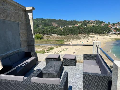 een balkon met een bank en stoelen en een strand bij CASA PLAYA DE LIMENS in Cangas de Morrazo