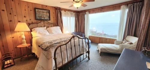 a bedroom with a bed and a chair and a window at PA Crows Nest Cottage in Port Angeles