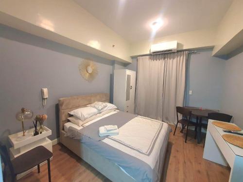 Minimalist Cozy Condo Studio Unit in Grand Residences Cebu في مدينة سيبو: غرفة نوم بسرير ومكتب وطاولة
