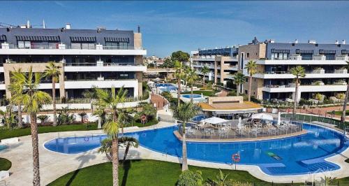 een resort met een groot zwembad en palmbomen bij Costa Blanca Livin Orihuela Costa, Flamenca Village in Orihuela