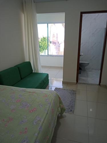 a bedroom with a bed and a couch and a window at Casa B de veraneio com estacionamento fechado in Ilha Comprida