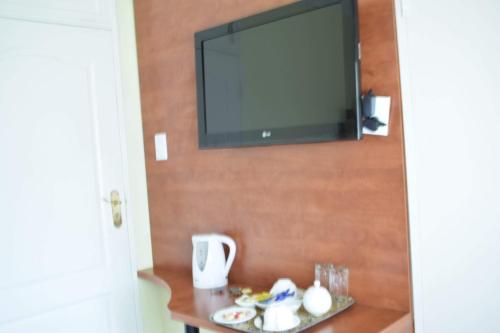 a television on a wall with a plate of food on a table at Lalela House in Johannesburg