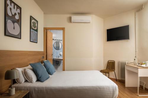 een slaapkamer met een bed, een bureau en een televisie bij BYPILLOW Erba in Girona