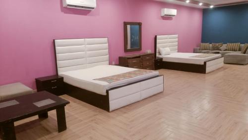 - 2 lits dans une chambre avec un mur rose dans l'établissement Hotel Versa Appartments lodges Gulberg3, à Lahore