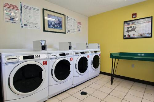 a laundry room with three washing machines and a green table at InTown Suites Extended Stay Select Corpus Christi TX in Corpus Christi