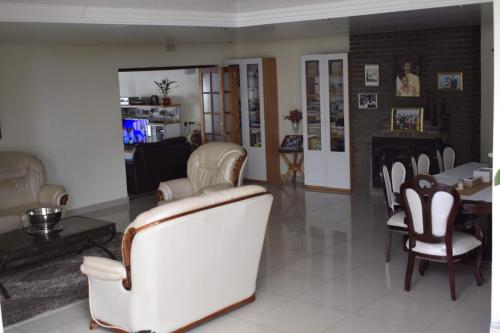 a living room with white chairs and a table at Lalela House in Johannesburg