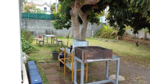 a grill in a yard next to a tree at Maison reposante in Le Tampon