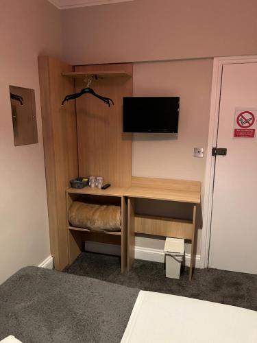 ロンドンにあるグッドウッド ホテルのデスク、壁掛けテレビが備わる客室です。
