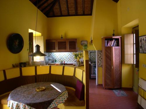 a room with a table and a kitchen with yellow walls at Quinta dos Reis in Alcantarilha