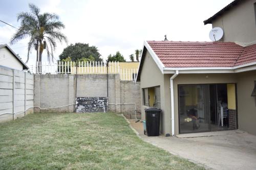 a house with a yard next to a fence at Lalela House in Johannesburg