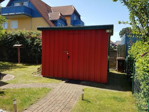 a red shed in front of a house at Haus Sonnenwind in Zingst