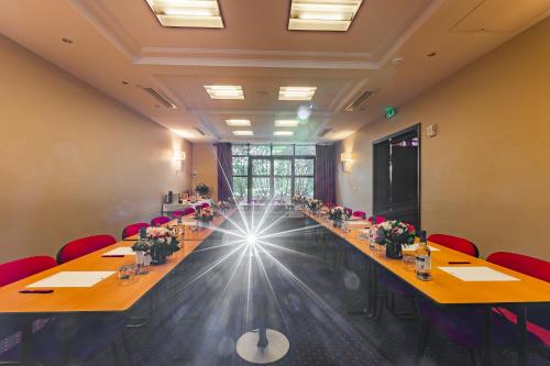 a large conference room with long tables and red chairs at Hotel de Berny in Antony