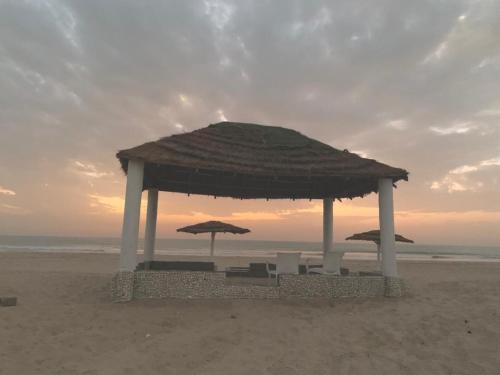 einen Pavillon mit Stühlen und Sonnenschirmen am Strand in der Unterkunft Bosofet Beach and Creek Lodge in Sanyang
