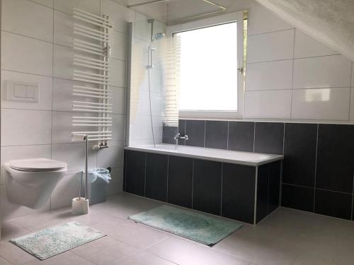 ein Bad mit einer Badewanne, einem WC und einem Fenster in der Unterkunft Ferienwohnung an der Nordsee in Sande