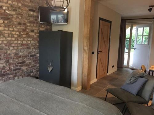 a bedroom with a bed and a brick wall at Gastenverblijf Bie Zus in Buggenum