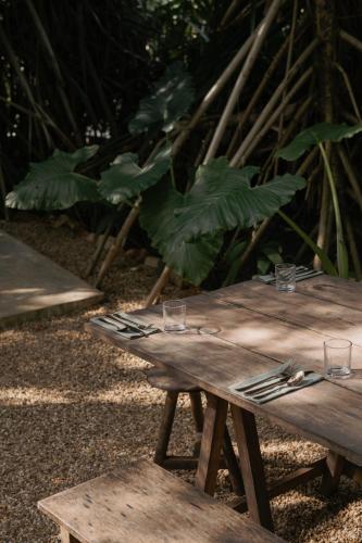 a wooden picnic table with glasses and utensils on it at The Kip in Ahangama