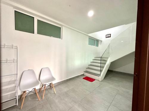 a room with two white chairs and a staircase at Springfield 3-Storey Cheerful Townhouse #Yoyo Homestay in Sandakan